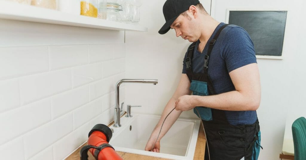 Plumber using drain snake to unclogging garbage disposal