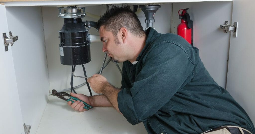 Plumber fixing a garbage disposal with allen wrench